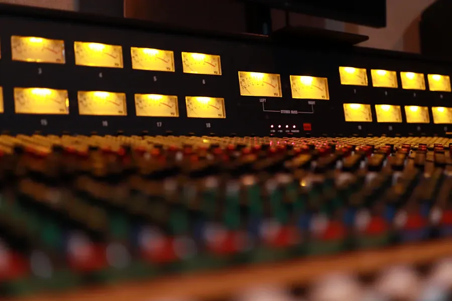 Close view of a warm-lit analogue mixing console with rows of faders and meters