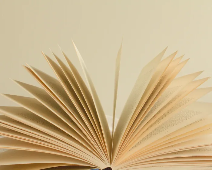 The pages of a book fanned open against a cream background