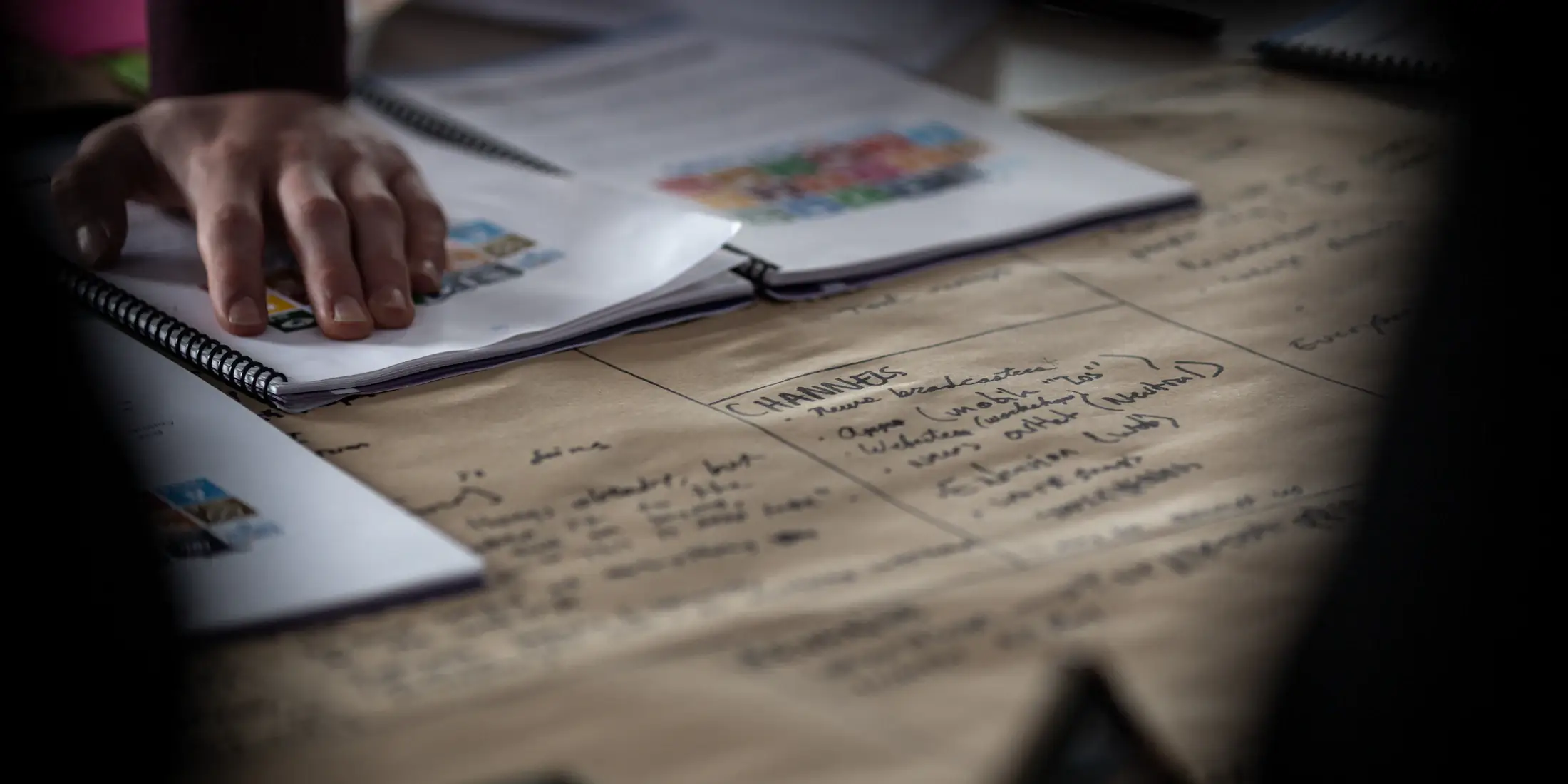 Hands working over manuscript pages on a desk
