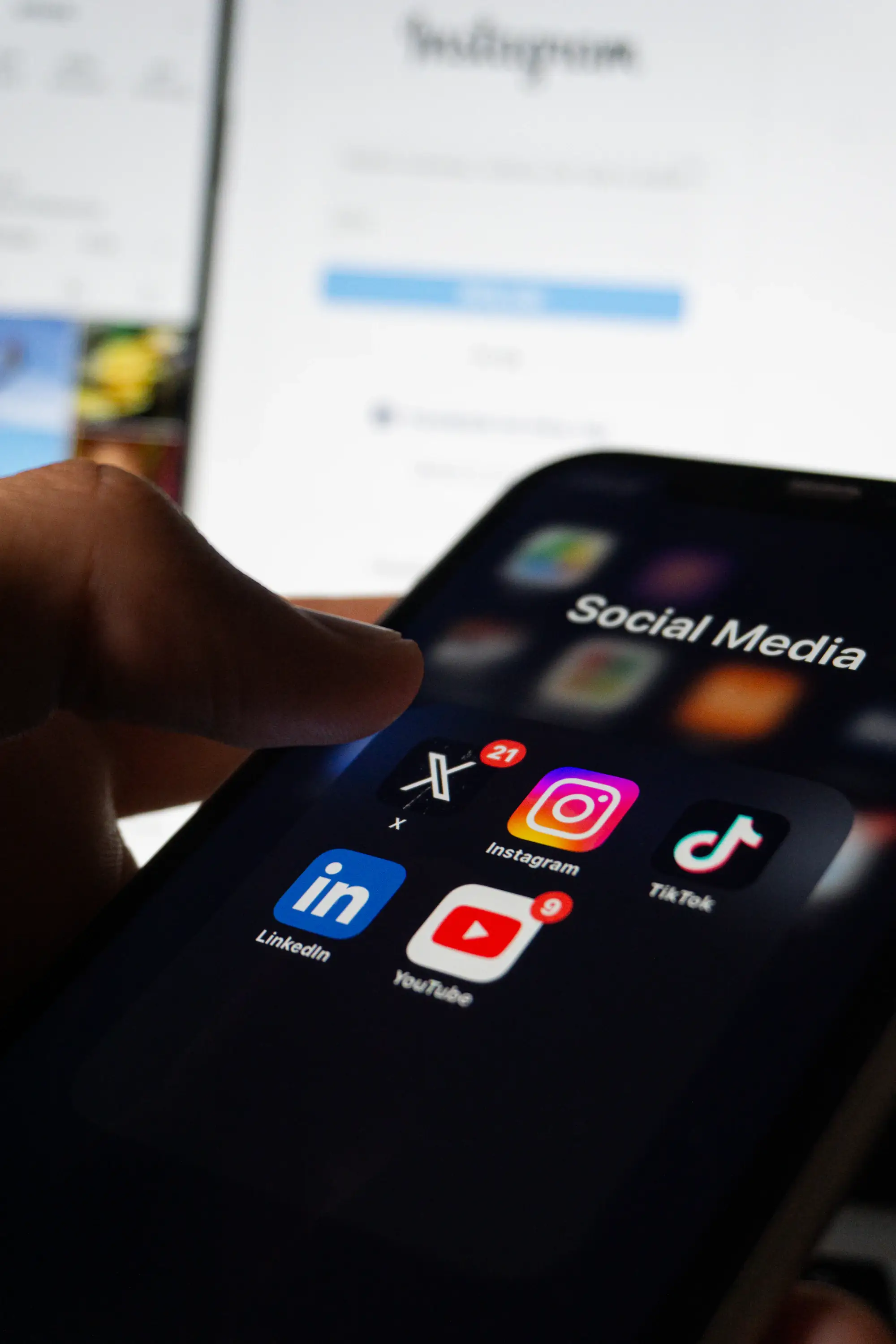 A hand holding a phone showing social media apps