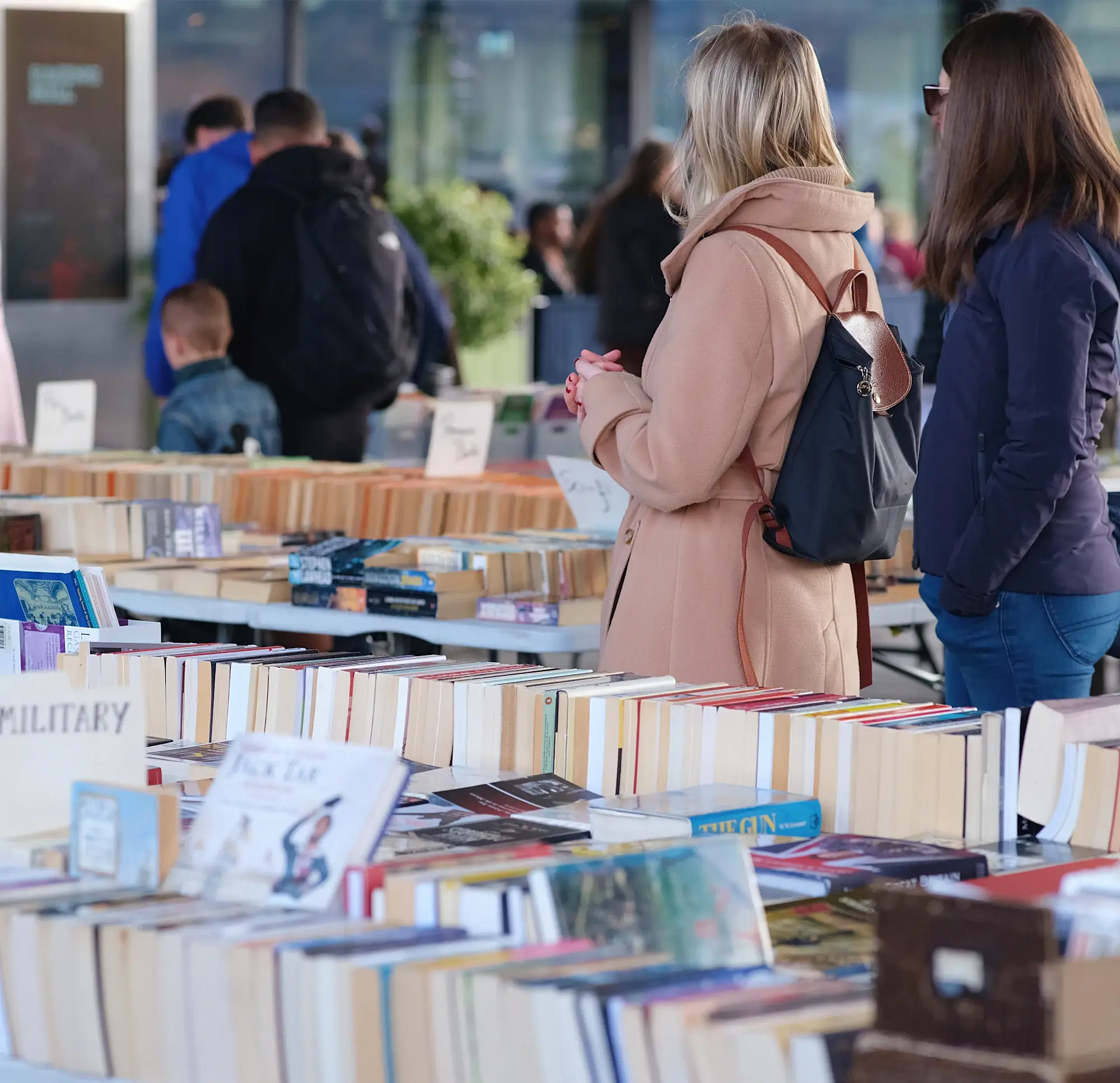 Visitors browsing tables of books at a book fair