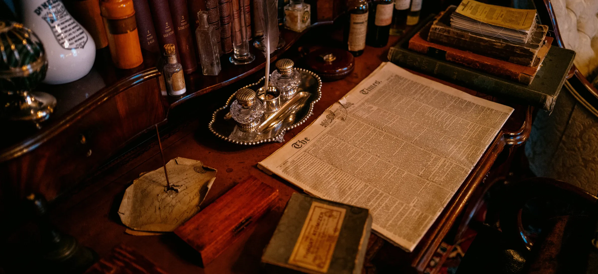 A writing desk covered with books, papers and an inkwell